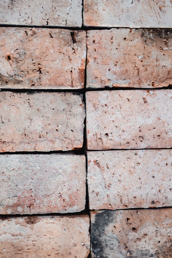 Detailed close-up of rustic clay bricks stacked in a vertical pattern, showcasing texture and structure.